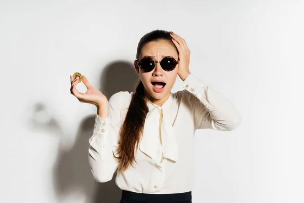 Rica chica feliz con gafas mira a la cámara y se aferra a la cabeza. Bitcoin, criptomoneda — Foto de Stock