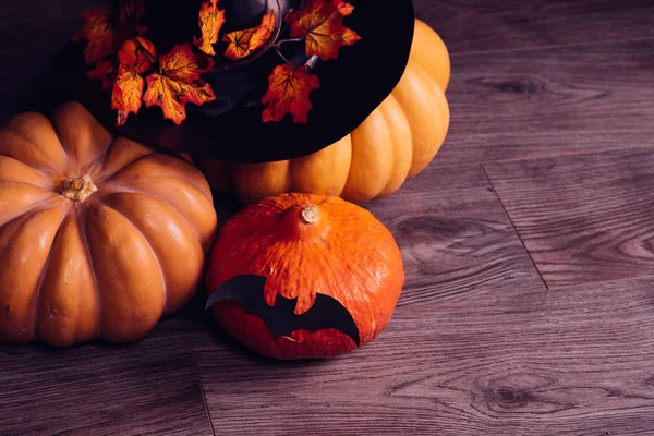 Cadılar Bayramı, siyah bir zemin üzerine altın sonbahar yaprakları ile süslenmiş siyah cadı şapka için büyük kabak