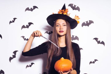 Mutlu Cadılar Bayramı seksi cadı ve sihirli bir değnek ve bir kabak kameraya arıyorum elinde siyah bir şapka ile. Cadı bir Cadılar Bayramı partisine gidiyordu. Yarasalar arka plan karşı izole