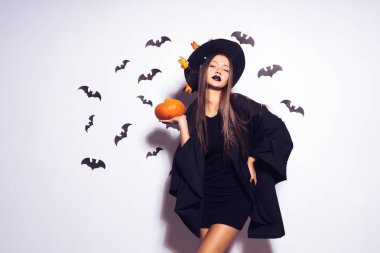 Halloween cadı uzun saçlı ve bir kabak ile. Siyah bir takım elbise giymiş bir güzel kız bir partiye gidiyor. Yarasalar arka planı. Geniş Cadılar Bayramı partisi sanat tasarım