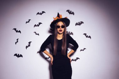 Kız cadı kameraya korkuttu. Bir parti yarasalar arka planı için siyah elbiseli güzel kız