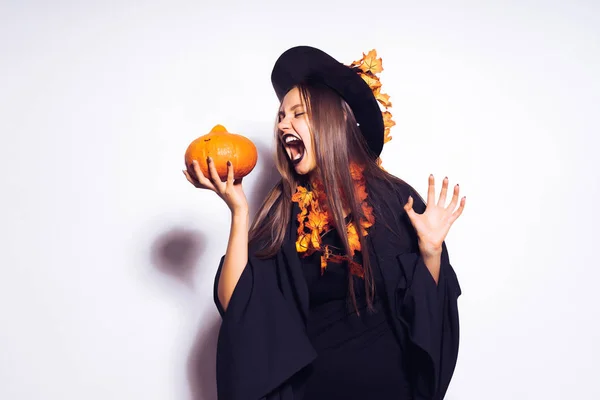 Bella ragazza pazza Halloween con i capelli lunghi. Una donna di Halloween in un abito nero di Halloween e indossa un cappello con foglie d'arancio . — Foto Stock