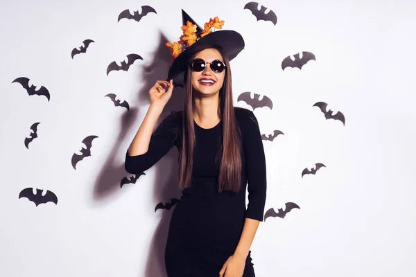 Halloween Party girl. Happy Halloween Sexy heks met een zwarte hoed. Mooie jonge lachende vrouw in heksen hoed en kostuum geïsoleerd op witte achtergrond — Stockfoto