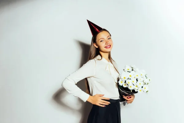 Menina feliz em um buquê de flores e um gorro de férias, aniversário, feriado, festa, diversão — Fotografia de Stock
