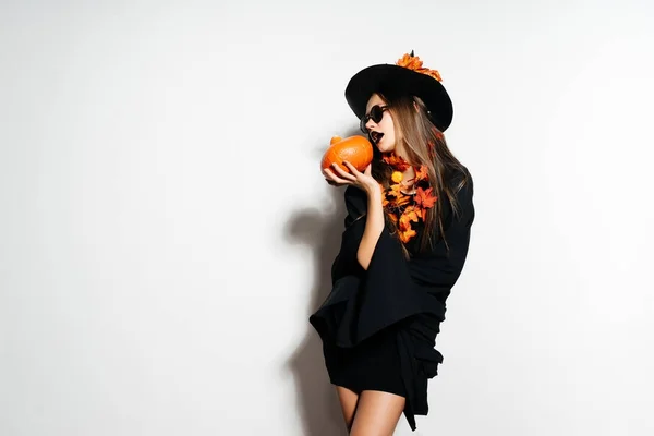 Strega di Halloween con una zucca e in occhiali. Ampia festa di Halloween art design. La ragazza vuole mangiare una zucca. La strega sta andando ad una festa — Foto Stock