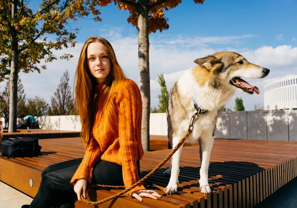 park ve kameraya arıyor bankta oturmuş güzel kızıl saçlı kız. sıcak sonbahar günü, güneşli havalarda