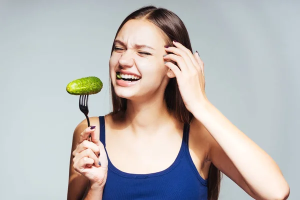 Flicka i en blå skjorta om en stor gurka. En hungrig tjej. Kost, hälsosam kost, läckra färska grönsaker. — Stockfoto