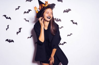 Kız cadı kameraya korkuttu. Bir parti yarasalar arka planı için siyah elbiseli güzel kız