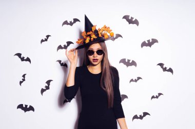 neşeli kız bir Cadılar Bayramı partisine gidiyor. Elbise, sonbahar turuncu yaprak üzerinde siyah bir şapka cadı