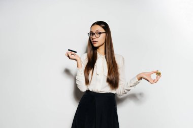 Güzel bir kız bir bluz ve gözlük bir banka kartı ve bir altın para tutuyor. Bitcoins, kripto para birimi. elektronik para.