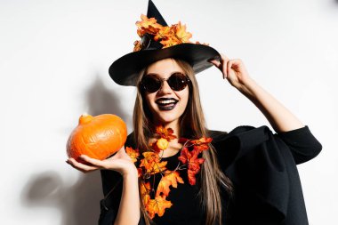 gülen Halloween cadı güneş gözlüklü küçük balkabağına tutar ve onun büyük şapka tutar. Cadılar Bayramı stil, Cadılar Bayramı partisi