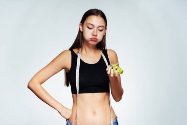 Güzel bir kız siyah top onun boynuna bir ölçüm bandı ile karanlık bir lahana yiyor. Diyet, güzel vücut, doğru beslenme.