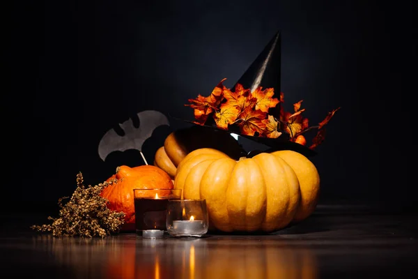 Cabeça de abóbora de Halloween, folhas de outono, chapéu terrível em um fundo preto, festa de Halloween — Fotografia de Stock