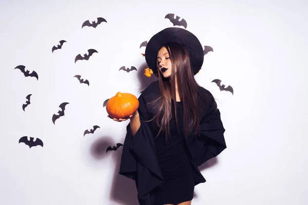 Széles Halloween party art design Halloween boszorkány egy faragott sütőtök és egy fekete szörnyű kalap mosolyog. A háttérben egy csomó denevérek. — Stock Fotó