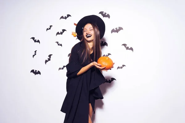Хэллоуинская ведьма с резной тыквой и темными очками Красивая молодая удивленная женщина в шапке и костюме ведьмы, держащая тыкву. Дизайн для Хэллоуина — стоковое фото
