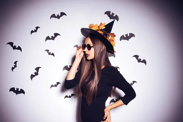 Breed Halloween party kunst design Halloween heks in een zwarte verschrikkelijke hoed glimlacht. Tegen de achtergrond van een bos van vleermuizen. — Stockfoto