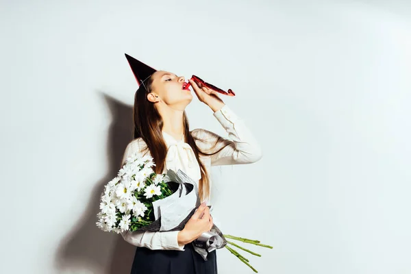 Lief meisje blazen in de pijp. Het meisje houdt een boeket van mooie bloemen. Gelukkige verjaardag, vakantie, plezier — Stockfoto