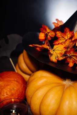 Sarı ve turuncu kabak üzerinde siyah bir şapka sarı sonbahar yaprakları etrafında bir cadı gibi yalan ve mumlar yanıyor, üniversite Cadılar Bayramı için bekliyor