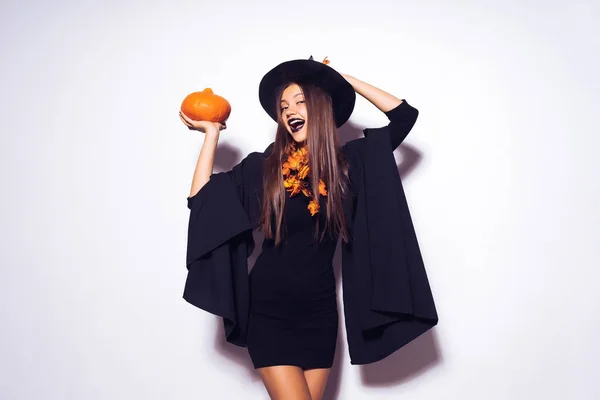 Šťastná dívka v Halloween kostýmu a to čarodějnický klobouk drží dýně — Stock fotografie