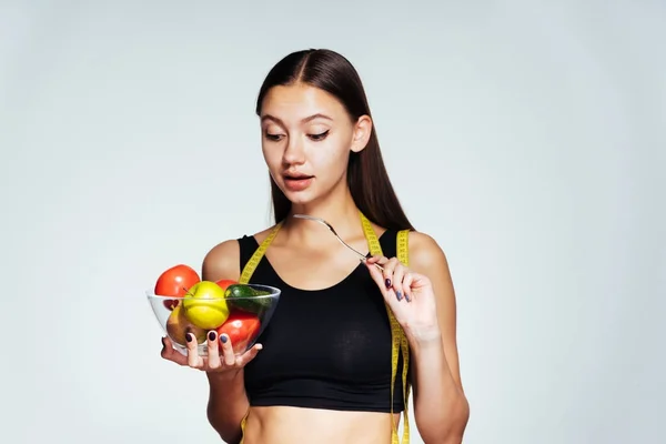 Smal atletisk tjej klockor sin figur och vill gå ner i vikt, innehar en tallrik med äpplen och en gaffel — Stockfoto