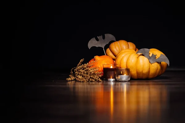 Amarelo e laranja Halloween abóboras mentira, ao lado das velas acesas e morcegos pintados — Fotografia de Stock