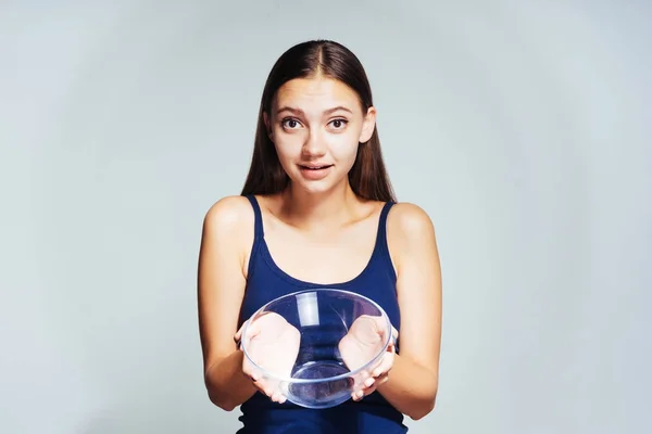 A young girl wants to be slim and beautiful, shows an empty plate and looks surprised — Stock Photo, Image