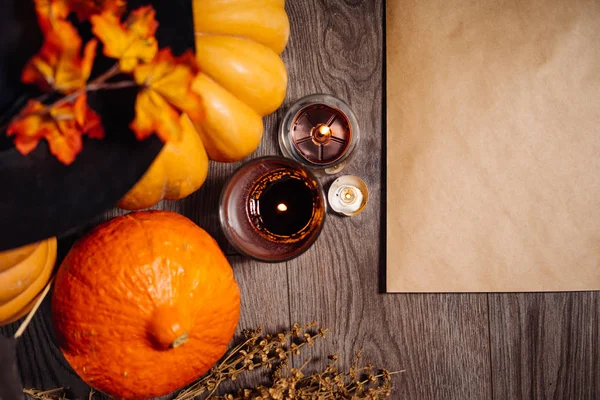 На деревянном столе оранжевые и желтые тыквы, свечи горят и лежат осенние листья, чтобы украсить дом на Хэллоуин — стоковое фото
