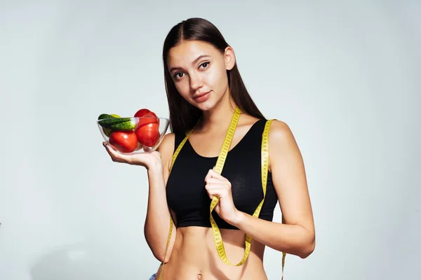Mladá dívka sportovní hodinky její postavu, drží desku s užitečné jablka ve svých rukou — Stock fotografie
