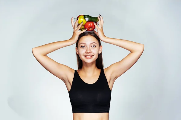 Jovem menina saudável sorri e segura um prato com legumes e frutas, gosta de comida saudável — Fotografia de Stock