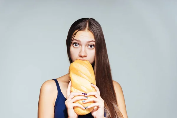 Aç genç kız hevesle beyaz kötü ekmek yiyor — Stok fotoğraf