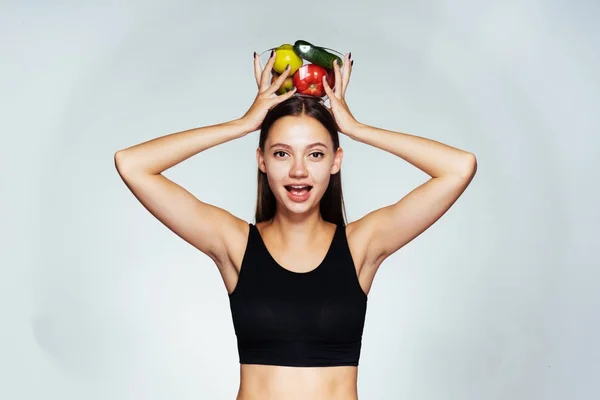 Mladá štíhlá dívka jí pouze zdravé zdravé jídlo, drží desku s jablky nad její hlavou — Stock fotografie