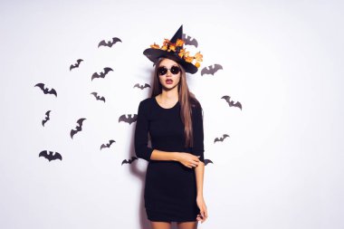 genç bir kız bir cadı Cadılar Bayramı için siyah bir şapka ile sarı yaprakların bir çelenk koymak giyinmiş