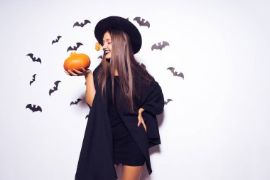 bir cadı bir turuncu kabak tutan Cadılar Bayramı için giyinmiş bir gülen kız