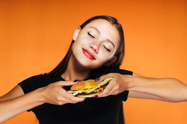 Mladá dívka chce zhubnout, úsměvy a drží škodlivé hamburger — Stock fotografie