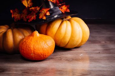 ahşap bir masa üzerinde bir cadının Cadılar Bayramı şapka ve sonbaharda akçaağaç yaprakları ile sarı ve turuncu su kabakları yalan