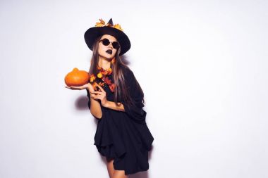 Cadılar Bayramı için bir cadı değişti güneş gözlüklü genç Gotik kaltak kız tutan bir kabak onun elinde