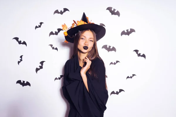 Une jeune gothique coiffée d'un chapeau de sorcière noir célèbre Halloween. sur fond de dessins de chauves-souris — Photo
