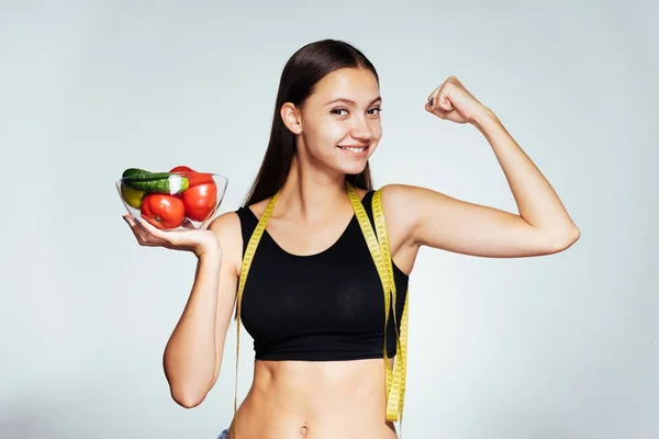 Uma menina sundry nova observa sua figura, prende um prato com vegetais úteis e frutas — Fotografia de Stock