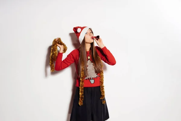 Joven feliz chica celebra el Año Nuevo y la Navidad, en una gorra roja, suéter festivo y oropel de oro —  Fotos de Stock
