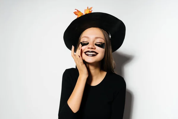 Una joven chica gótica riendo en un sombrero de bruja negro se regocija en Halloween — Foto de Stock