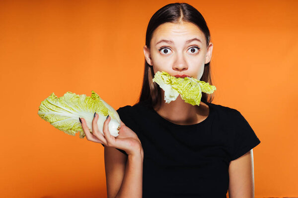 young surprised frustrated girl wants to lose weight, eats Pekinese cabbage
