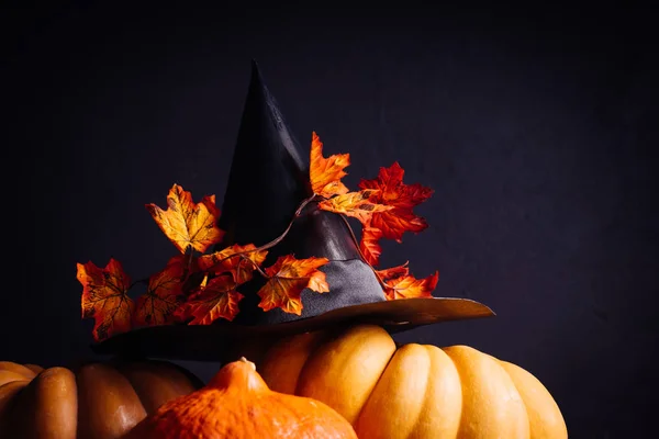 Sammansättning för att dekorera ett hus för halloween, gula och orange pumpor, en svart häxa hatt dekorerad med lönnlöv — Stockfoto