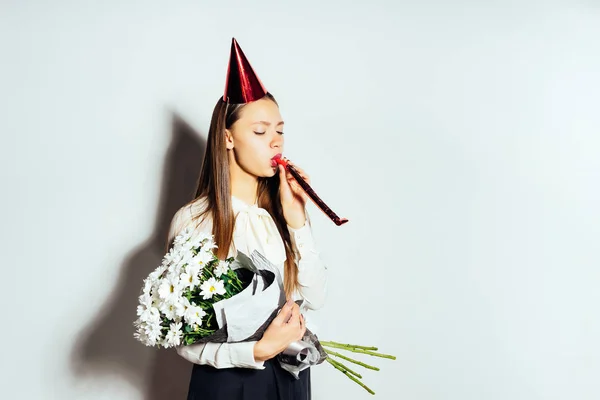 Niña celebra su cumpleaños en una gorra roja, tiene un ramo de flores blancas en sus manos — Foto de Stock