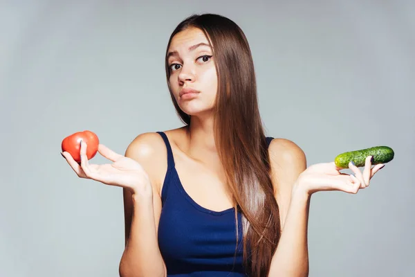 Jeune fille affamée veut perdre du poids, tient un concombre et une tomate — Photo