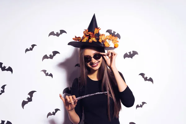 Riéndose alegre chica en forma de bruja en halloween, usando gafas de sol, sosteniendo una varita mágica —  Fotos de Stock