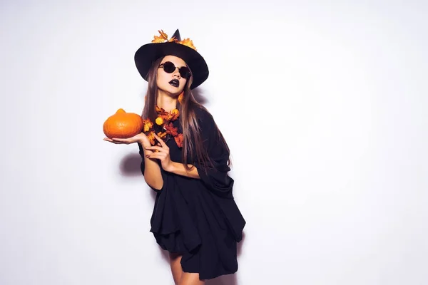 Dívka Mladá gothic čubka v sluneční brýle přeměnit čarodějnice halloween, drží dýně ve svých rukou — Stock fotografie