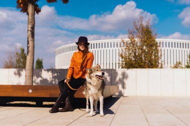 gülümseyerek, onun köpeği ile ahşap bir bankta oturan genç Kızıl saçlı kız