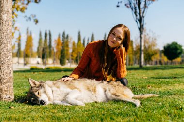 Kızıl saçlı kız büyük köpeğiyle yeşil çimenlerin üzerinde yürüyüş