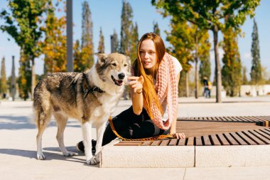 gülümseyerek, onun köpeği ile ahşap bir bankta oturan genç Kızıl saçlı kız