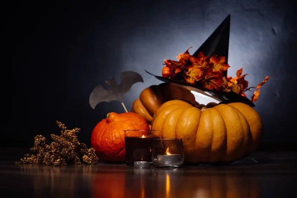 Een compositie voor het versieren van een huis voor halloween, oranje en geel pompoenen, geurkaarsen, een zwarte heks hoed branden — Stockfoto